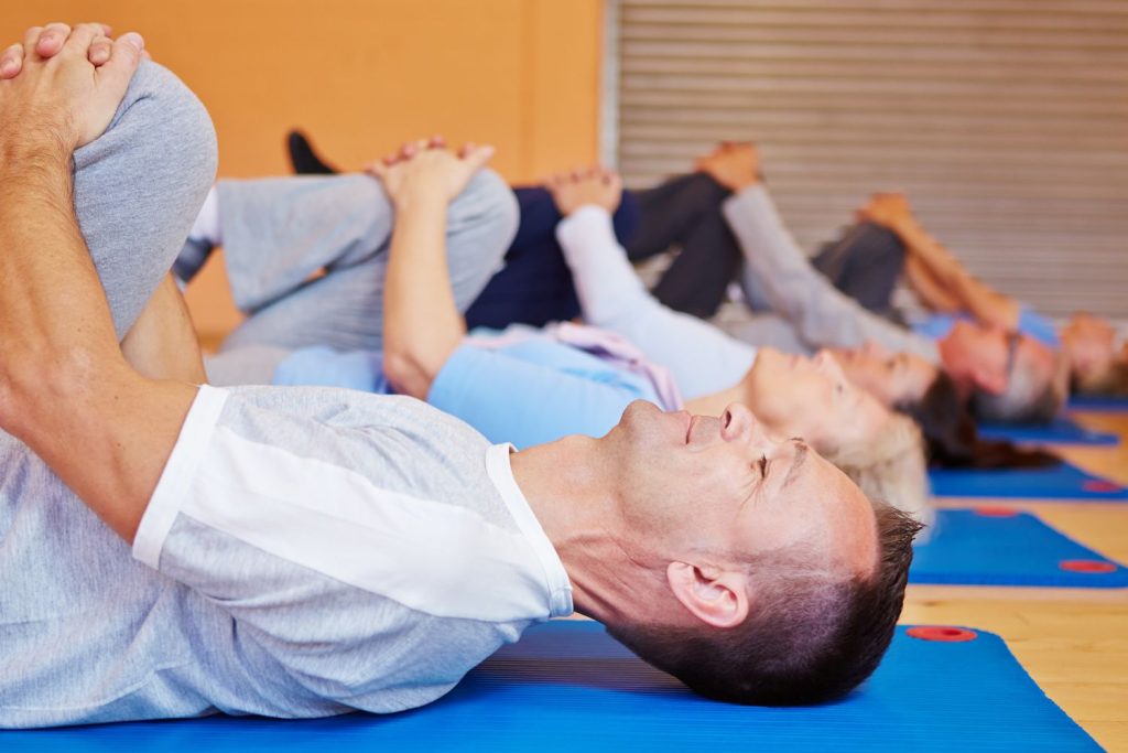 People lying down in yoga mat doing mobility training